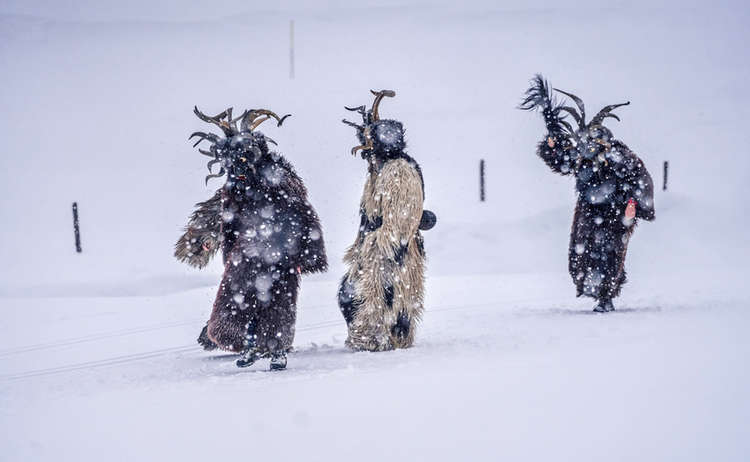 "Der Pass": Drei Krampus-Gestalten laufen durch die verschneite Landschaft.